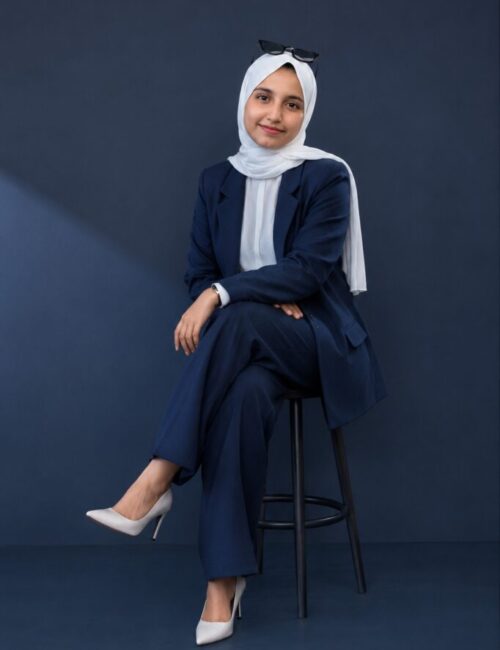 Confident Digital Marketing Strategist in Kannur sitting in a professional studio wearing a navy blue suit and white hijab.
